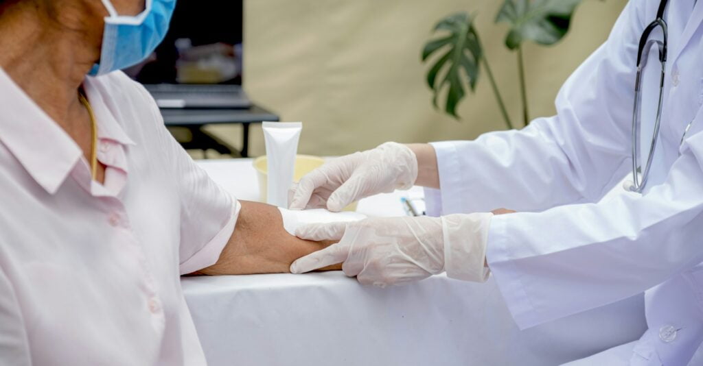 The doctor's hand is making a wound on the arm of an elderly woman who has an accident